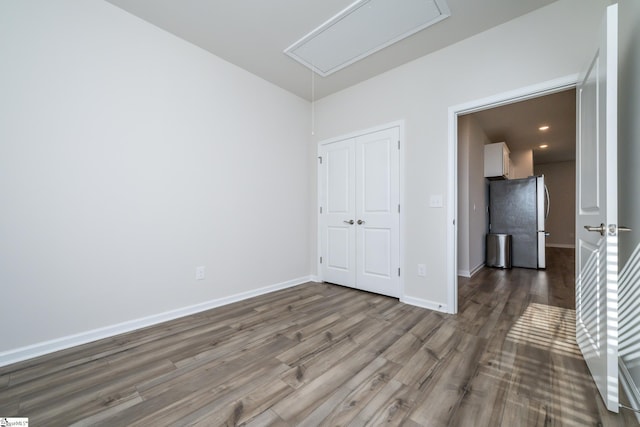 unfurnished bedroom with dark hardwood / wood-style floors, stainless steel refrigerator, and a closet