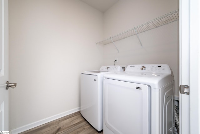 clothes washing area with washing machine and dryer and light hardwood / wood-style flooring