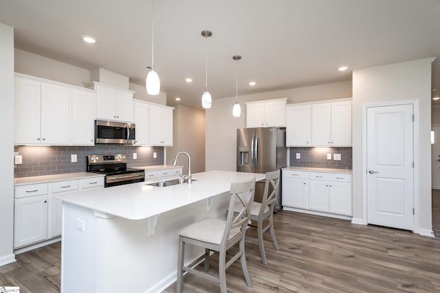 kitchen with white cabinets, appliances with stainless steel finishes, dark hardwood / wood-style floors, and hanging light fixtures