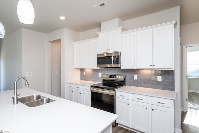 kitchen with dark wood-type flooring, hanging light fixtures, sink, appliances with stainless steel finishes, and white cabinetry