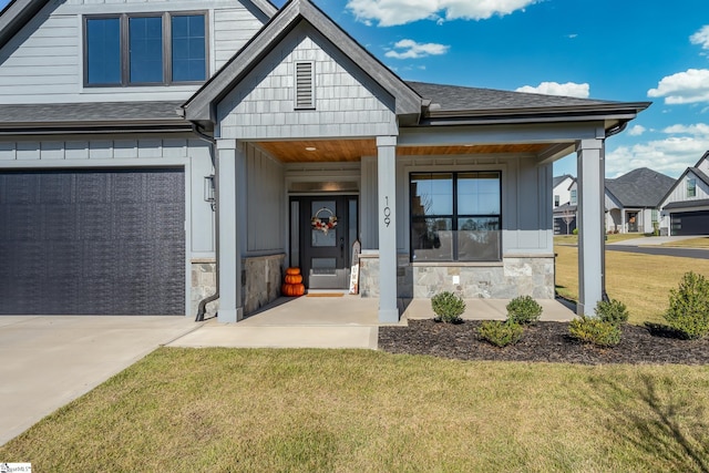 view of front of home featuring covered porch, a garage, and a front yard