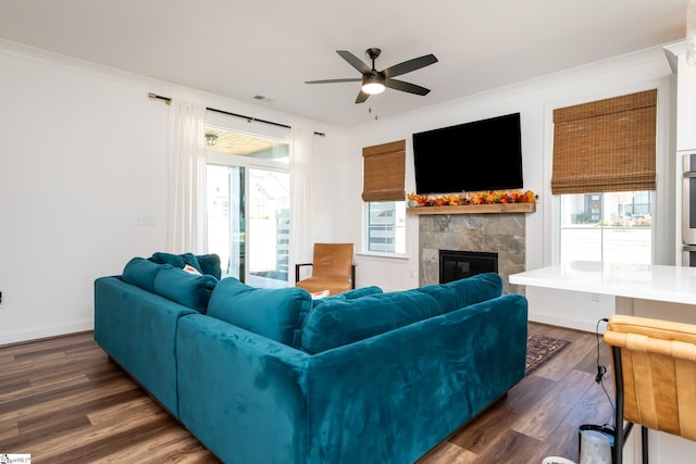 living room featuring a tiled fireplace, plenty of natural light, dark hardwood / wood-style floors, and ornamental molding