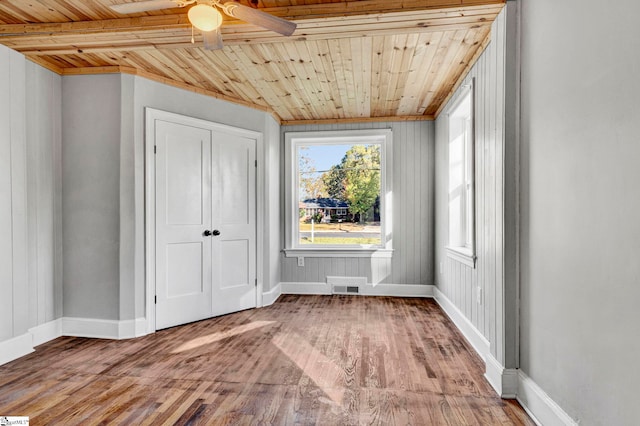 unfurnished bedroom featuring ceiling fan, light wood-type flooring, wooden ceiling, and a closet