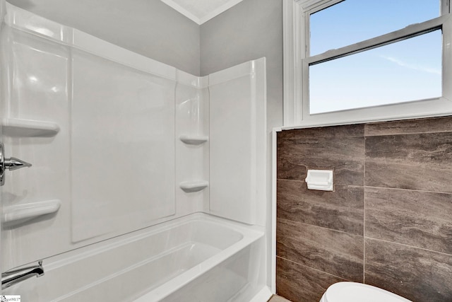 bathroom featuring crown molding, shower / bath combination, tile walls, and toilet