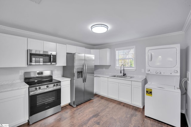 kitchen featuring sink, stacked washing maching and dryer, dark hardwood / wood-style flooring, white cabinetry, and stainless steel appliances