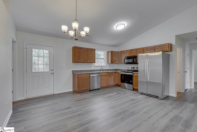 kitchen with light wood-type flooring, stainless steel appliances, vaulted ceiling, and a healthy amount of sunlight