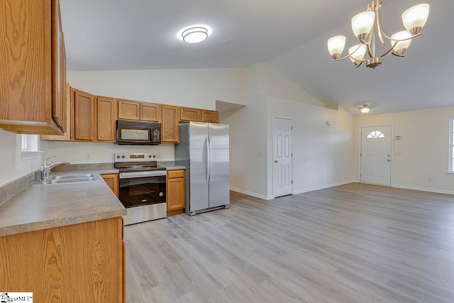 kitchen with pendant lighting, sink, vaulted ceiling, appliances with stainless steel finishes, and light hardwood / wood-style floors