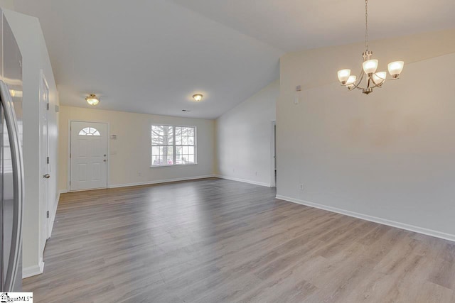 interior space featuring a chandelier, light wood-type flooring, and vaulted ceiling