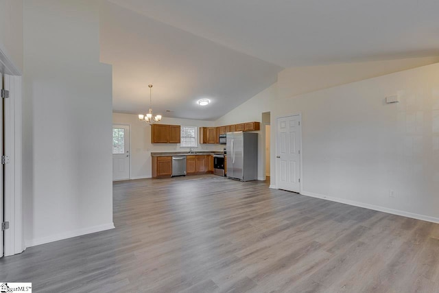 unfurnished living room with sink, light hardwood / wood-style flooring, lofted ceiling, and a notable chandelier