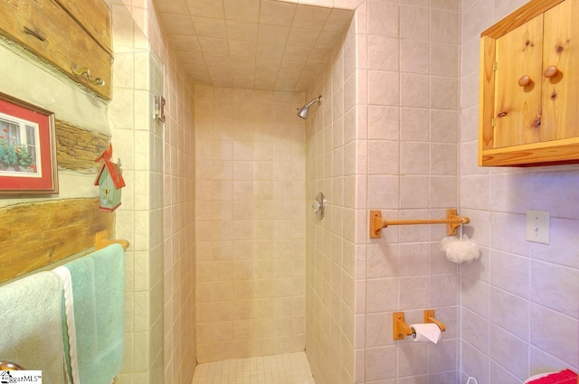 bathroom with a tile shower and tile walls