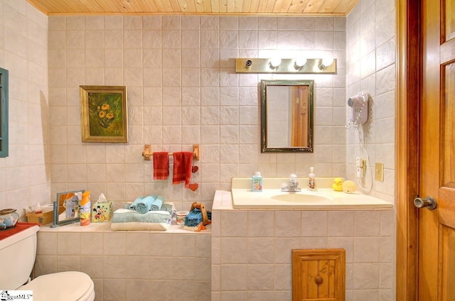 bathroom with vanity, toilet, wooden ceiling, and tile walls