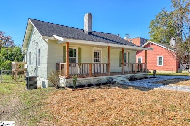 single story home with cooling unit, covered porch, and a front lawn