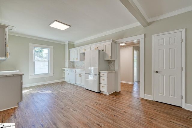 kitchen featuring light wood-type flooring, backsplash, ornamental molding, white appliances, and white cabinetry