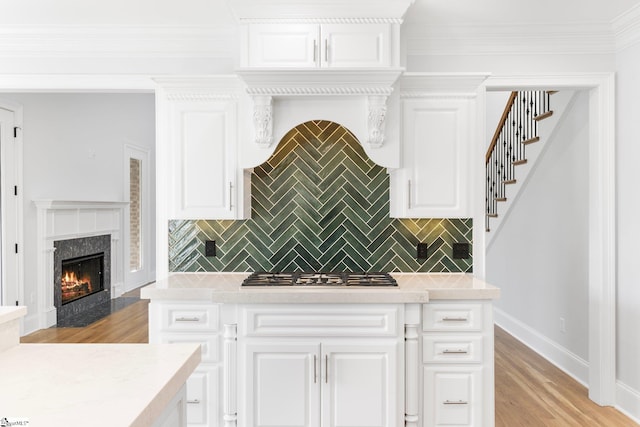 kitchen featuring white cabinetry, decorative backsplash, light hardwood / wood-style floors, and stainless steel gas stovetop