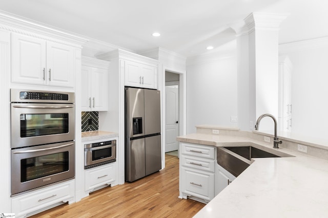 kitchen featuring sink, stainless steel appliances, light hardwood / wood-style floors, white cabinets, and ornamental molding