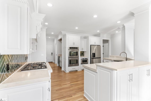 kitchen featuring decorative backsplash, light wood-type flooring, stainless steel appliances, sink, and white cabinetry