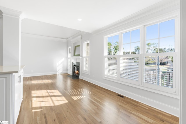 unfurnished living room with light wood-type flooring and crown molding