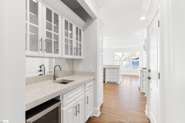 bar with white cabinetry, sink, light stone countertops, wine cooler, and light hardwood / wood-style flooring