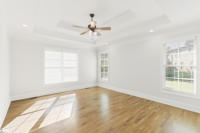 empty room featuring a raised ceiling, crown molding, and light hardwood / wood-style floors