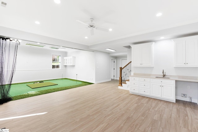 basement featuring light wood-type flooring, ceiling fan, and sink