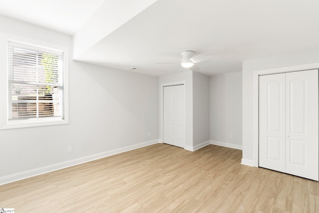 unfurnished bedroom featuring ceiling fan, light hardwood / wood-style flooring, and two closets