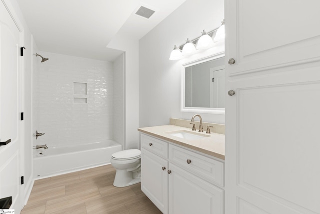 full bathroom featuring vanity, tiled shower / bath combo, and toilet