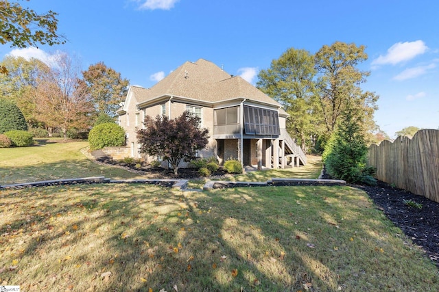 rear view of property featuring a sunroom and a yard