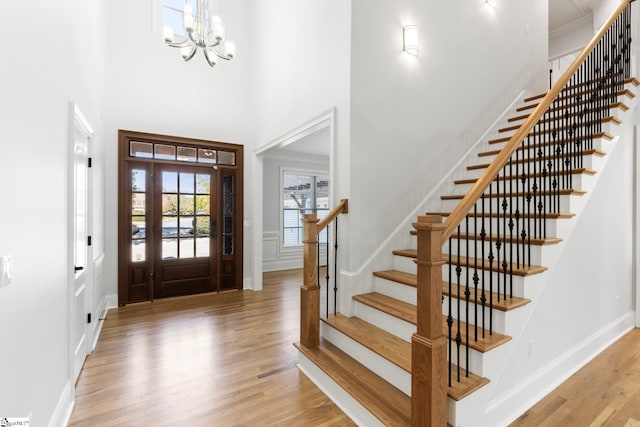 foyer featuring a towering ceiling, a notable chandelier, and light wood-type flooring