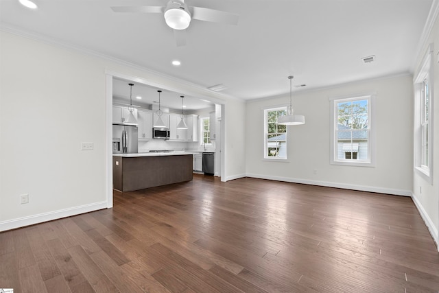 unfurnished living room with ceiling fan, dark wood-type flooring, and ornamental molding