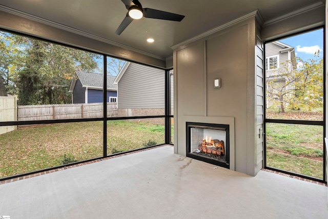 unfurnished sunroom with a fireplace, plenty of natural light, and ceiling fan