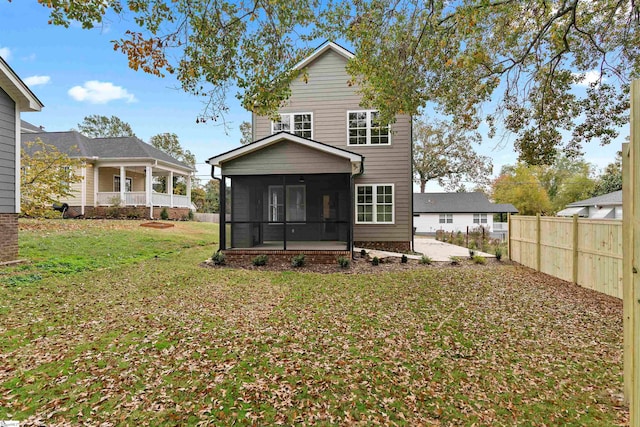 back of house featuring a lawn and a sunroom