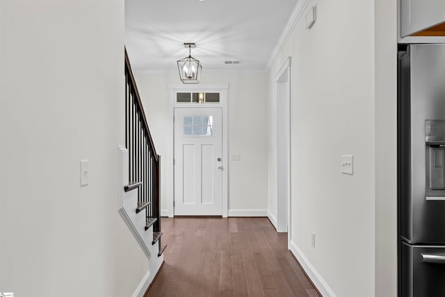 foyer with hardwood / wood-style flooring, crown molding, and a notable chandelier