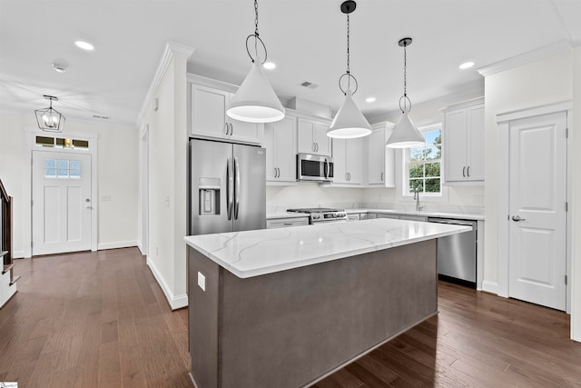 kitchen featuring pendant lighting, white cabinets, appliances with stainless steel finishes, a kitchen island, and dark hardwood / wood-style flooring