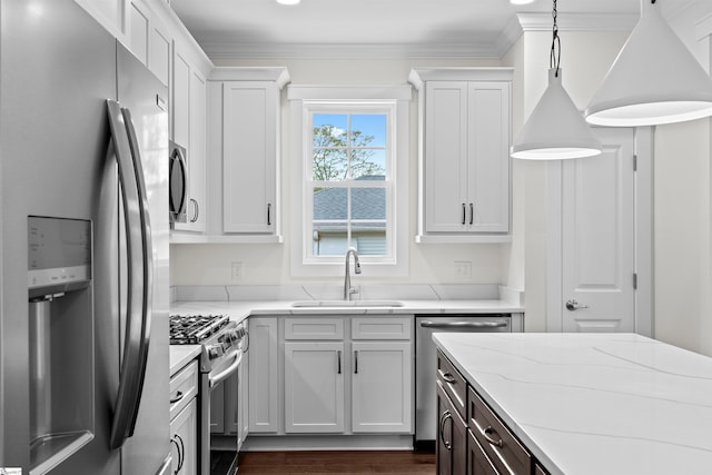 kitchen featuring appliances with stainless steel finishes, light stone counters, sink, pendant lighting, and white cabinetry