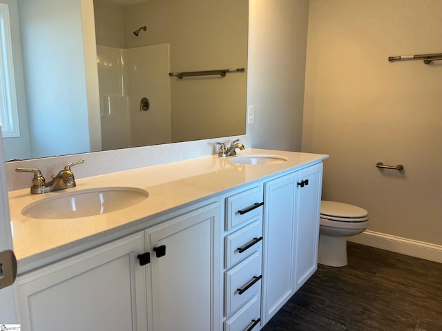 bathroom with wood-type flooring, vanity, toilet, and walk in shower