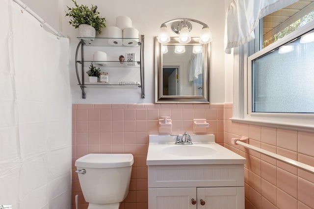 bathroom featuring vanity, tile walls, and toilet