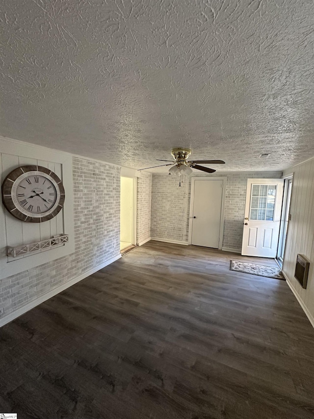 unfurnished living room with ceiling fan, a textured ceiling, and brick wall