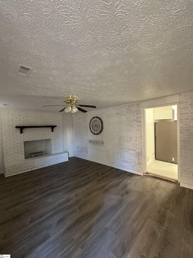 unfurnished living room with ceiling fan, dark hardwood / wood-style flooring, brick wall, and a brick fireplace