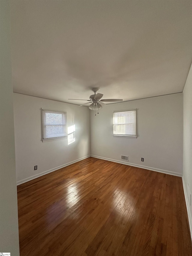 unfurnished room featuring ceiling fan, plenty of natural light, and dark wood-type flooring