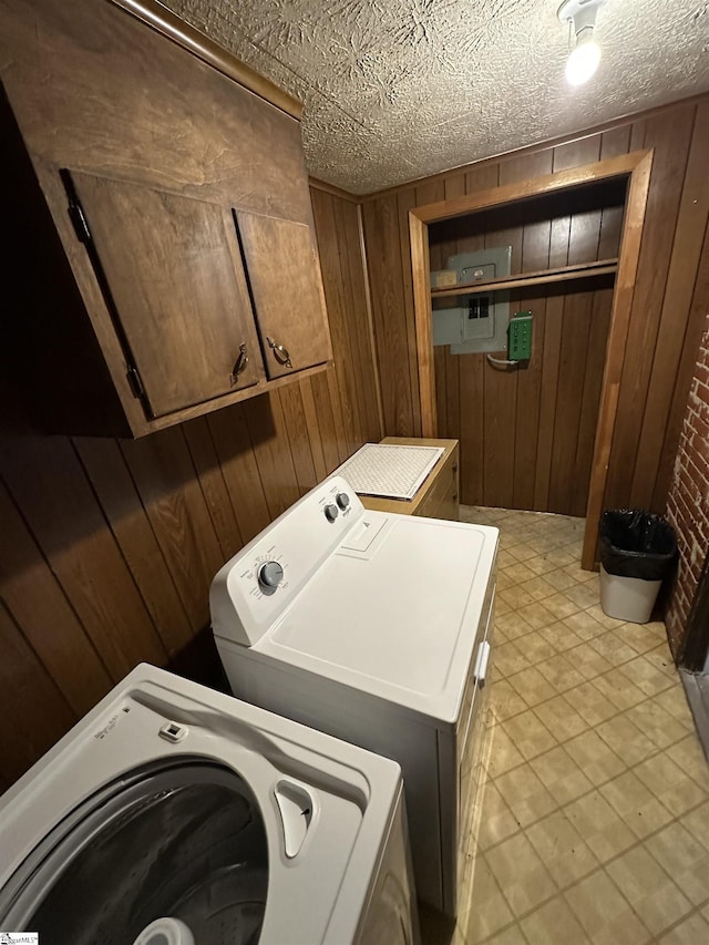 washroom featuring wooden walls, cabinets, and washer and dryer