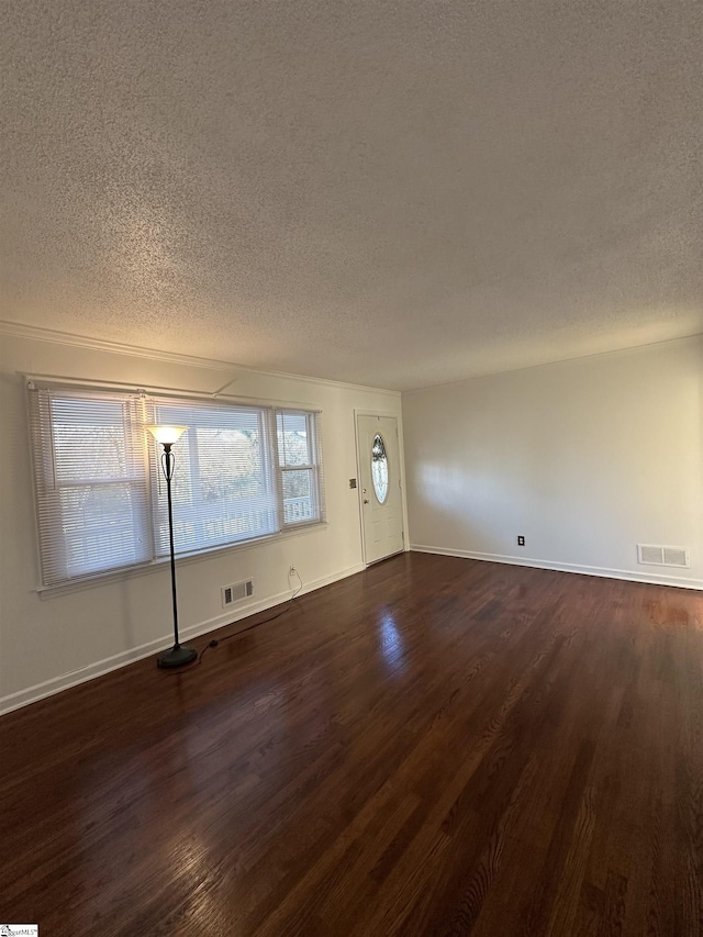 empty room with dark wood-type flooring and a textured ceiling