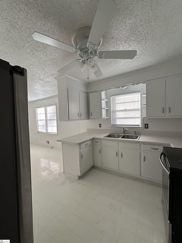 kitchen with white cabinets, a wealth of natural light, ceiling fan, sink, and black electric range