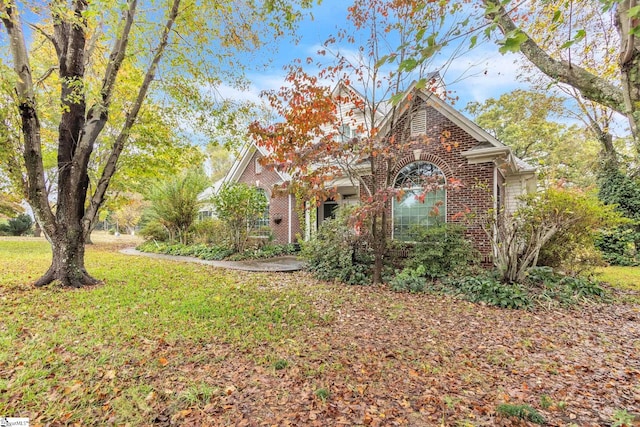 obstructed view of property featuring brick siding and a front lawn