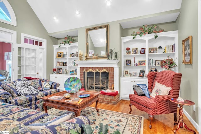 living area featuring vaulted ceiling, built in shelves, a fireplace, and wood finished floors