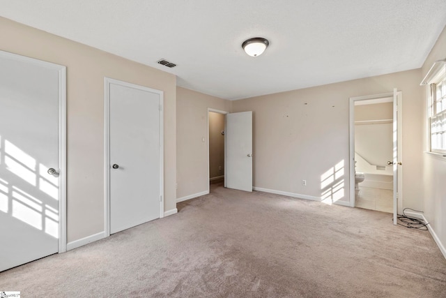 unfurnished bedroom with connected bathroom and light colored carpet