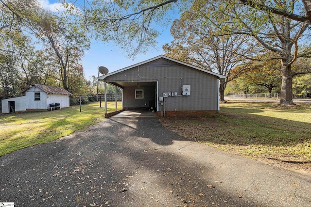 view of front facade with a carport, an outbuilding, and a front lawn