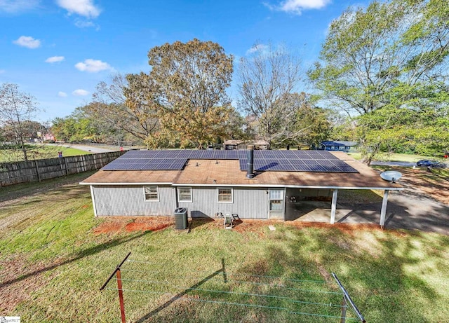 back of house featuring solar panels, cooling unit, and a yard