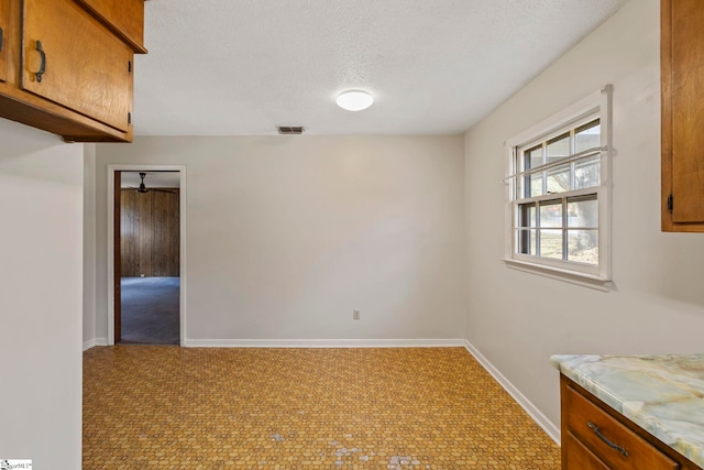 empty room with ceiling fan and a textured ceiling