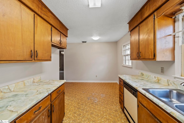 kitchen with stainless steel dishwasher, light tile patterned floors, sink, and a textured ceiling