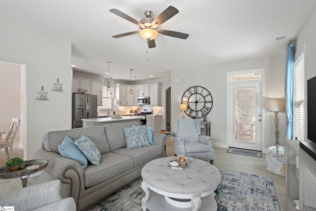 living room with ceiling fan and light hardwood / wood-style floors